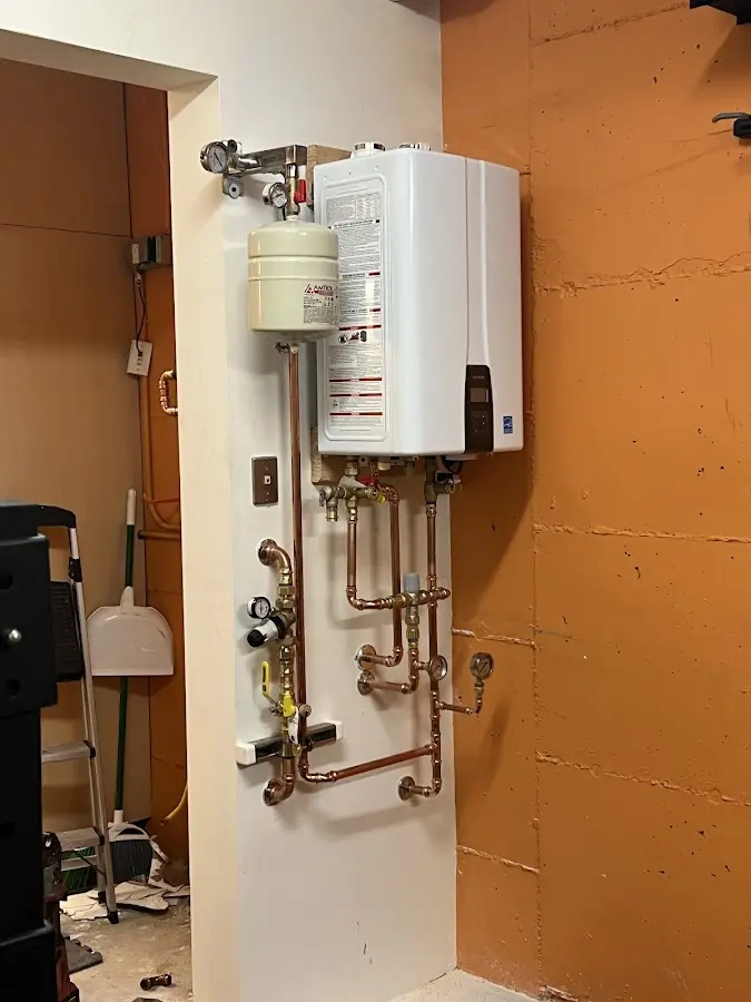 Plumbing technician inspecting water heater connections in Huntington